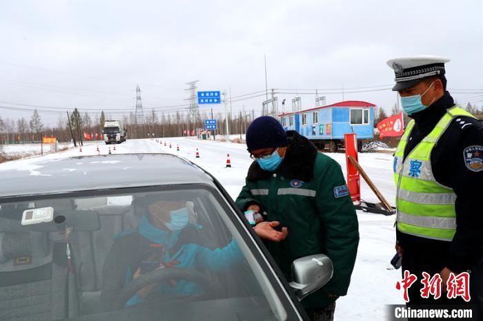 漠河市入城口工作人员冒雪检查来往车辆。　王景阳 摄